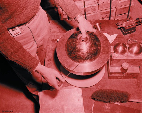 A red-tinted historical photograph depicting a person handing a metal object.