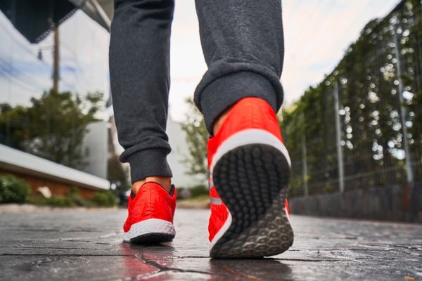 Lower Legs of a man walking in orange sneakers and grey jogging pants